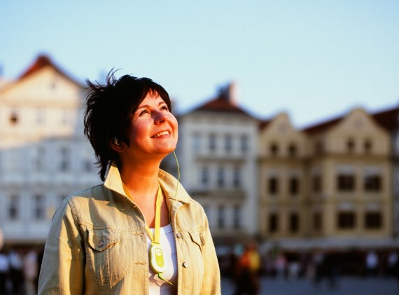 A happy tourist girl listening electronic tour guide in Prague